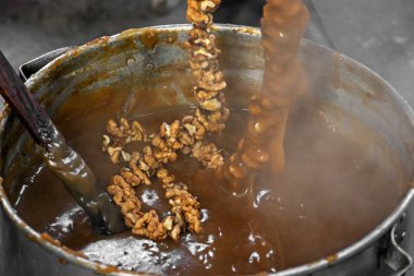 Geleneksel Ermeni tatlı Sujuk 'un (Churchkhela) hazırlanma süreci. Un katılmış üzüm suyundan yapılan kabuklu ceviz (fındık).