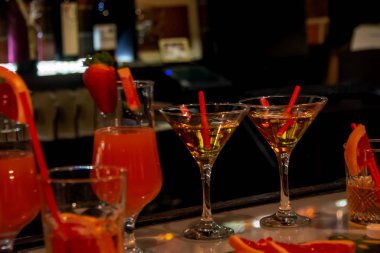 Alkol barı, bar tezgahında farklı kokteyl bardakları koyu bulanık arka plan, barda parlak kırmızı kokteyl bardakları, kokteyller. 