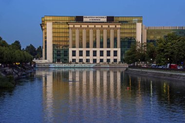 Bükreş, Romanya - 06 Ağustos 2019: Gölün önündeki Romanya Ulusal Kütüphanesi 'nin günbatımında yansıyan manzarası