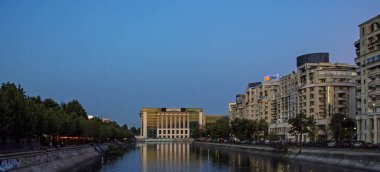 Bükreş, Romanya - 06 Ağustos 2019: Gölün önündeki Romanya Ulusal Kütüphanesi 'nin günbatımında yansıyan manzarası