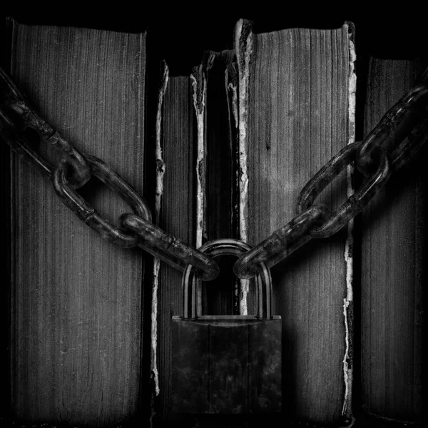 Old books strapping a rusty chain. Forbidden literature, old works artists locked with old padlock. Concept freedom of the press, unwanted literature and importance of right education. Black and white photography