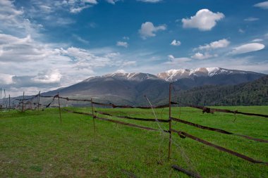 Dağları olan güzel yeşil doğa ve basit paslı metal çitlerin arkasında mavi gökyüzü. Perspektif görünümü