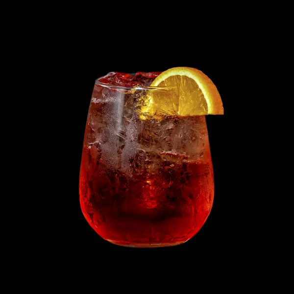 レモンのスライスと氷で飾られた赤いフルーツカクテルとガラス 黒の背景に隔離されたクローズアップ — ストック写真