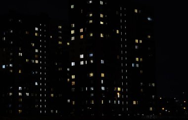 Cam ve çelik aydınlatma yakın görüntüsünden yapılmış çok katlı bir binanın penceresinde yanıp sönen ışık. Karanlıkta