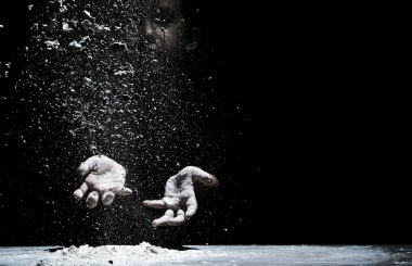 Little cute girl chef cooking with white flour on black background