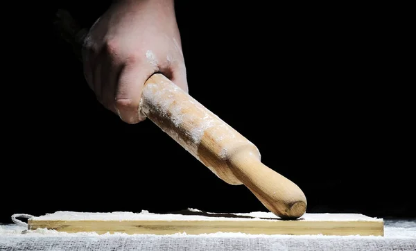 Um chef com as mãos na farinha está se preparando para cozinhar uma refeição em um fundo preto — Fotografia de Stock