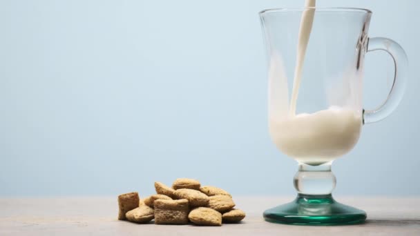 Melk wordt in een glas gegoten. havermoutpads op tafel — Stockvideo