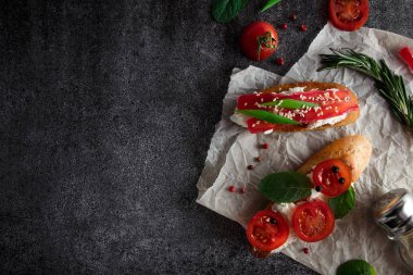 Domates, biber ve karanlık bir arka plan üzerinde yeşillik ile İtalyan bruschetta. Yukarıdan görüntülemek.