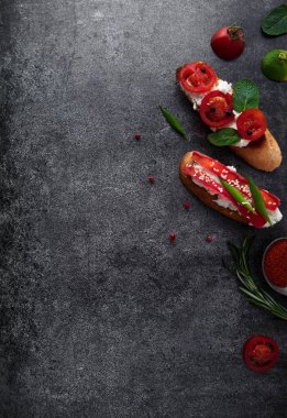 Domates, biber ve karanlık bir arka plan üzerinde yeşillik ile İtalyan bruschetta. Yukarıdan görüntülemek.