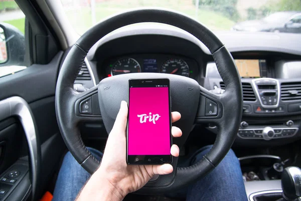 Bestuurder, houder van de smartphone met toepassing van de Trip.com — Stockfoto