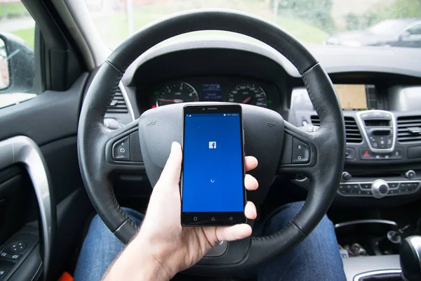 Bestuurder, houder van de smartphone met Facebook applicatie — Stockfoto