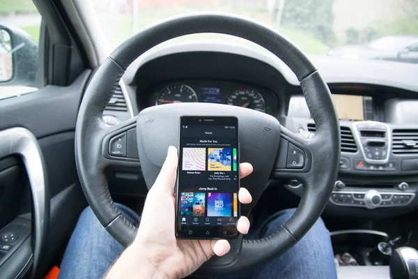 Driver segurando smartphone com aplicativo Spotify — Fotografia de Stock