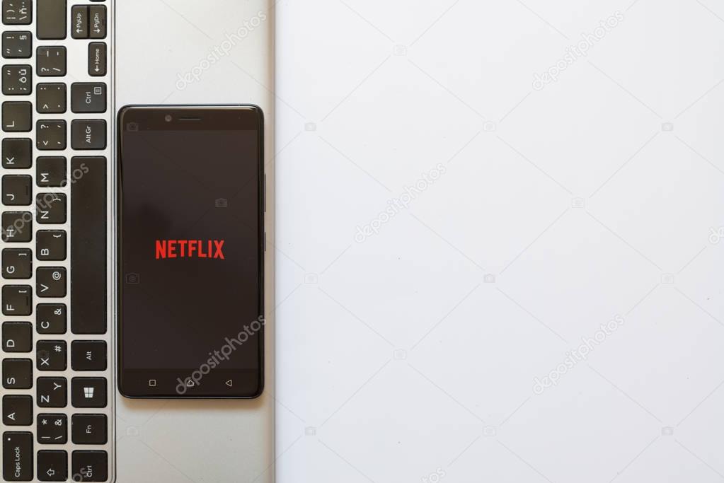 Los Angeles, USA, july 18, 2017: Netflix logo on smartphone screen placed on the laptop on white background.