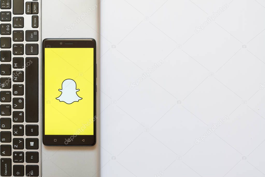 Los Angeles, USA, july 18, 2017: Snapchat logo on smartphone screen placed on the laptop on white background.