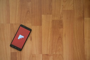 Flipboard logo üstünde smartphone perde ahşap arka plan üzerinde.