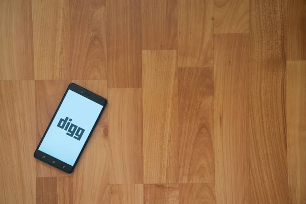 Digg logo na obrazovku smartphonu na dřevěné pozadí. — Stock fotografie