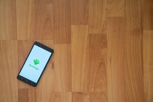 Logotipo de Duolingo en la pantalla del smartphone sobre fondo de madera . — Foto de Stock