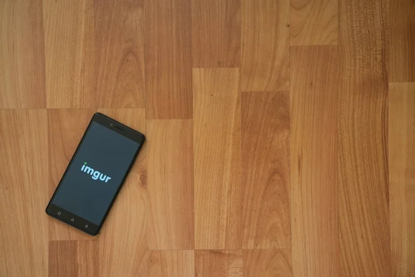 Logotipo de Imgur en la pantalla del teléfono inteligente sobre fondo de madera . — Foto de Stock