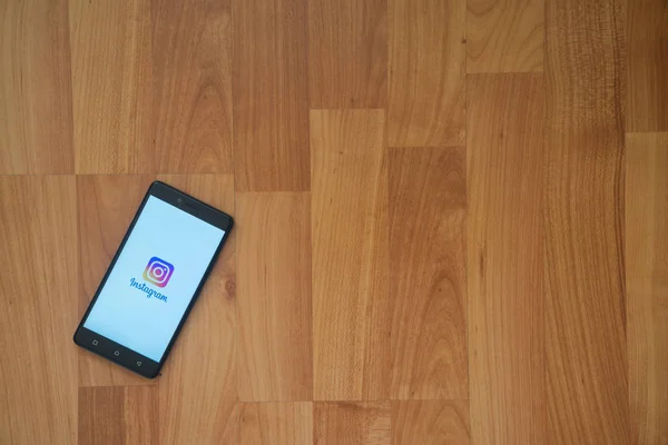 Logo de Instagram en la pantalla del smartphone sobre fondo de madera . — Foto de Stock