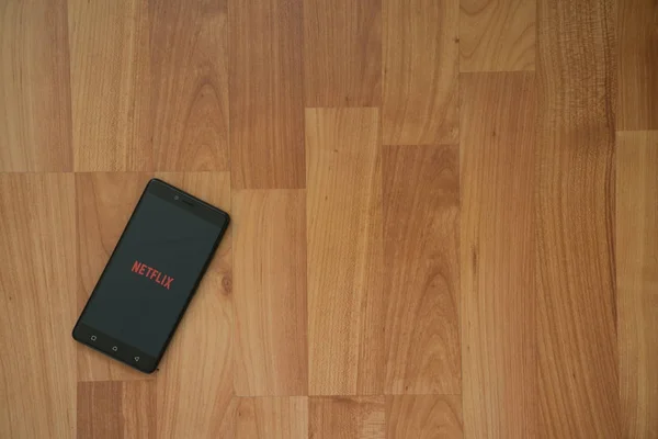 Logo de Netflix en la pantalla del teléfono inteligente sobre fondo de madera . — Foto de Stock