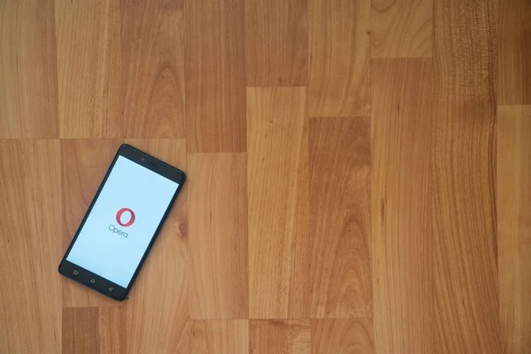 Logo Opera mini en la pantalla del teléfono inteligente sobre fondo de madera . — Foto de Stock