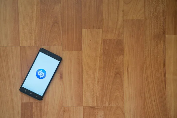 Shazam λογότυπο στην οθόνη του smartphone σε φόντο ξύλινη. — Φωτογραφία Αρχείου