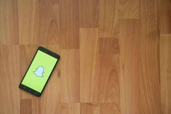 Snapchat logo üstünde smartphone perde ahşap arka plan üzerinde. — Stok fotoğraf