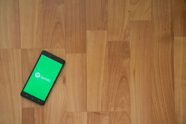 Spotify logo na obrazovku smartphonu na dřevěné pozadí. — Stock fotografie