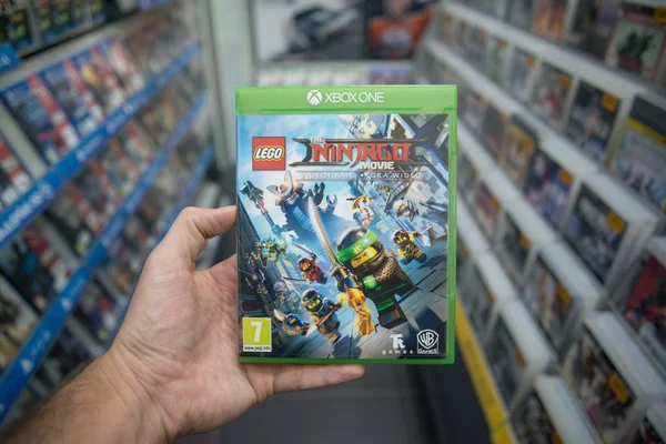 Homme tenant Lego Ninjago jeu vidéo sur la console Microsoft XBOX One en magasin — Photo