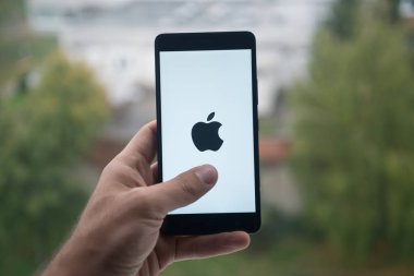Üstünde belgili tanımlık perde smartphone ile elma logosu ile parmak tutan adam.