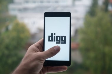 Üstünde belgili tanımlık perde smartphone parmak ile Digg logolu tutan adam.