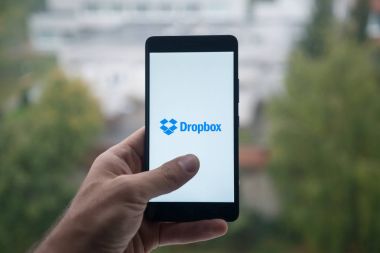 Üstünde belgili tanımlık perde smartphone parmak ile Dropbox logolu tutan adam.
