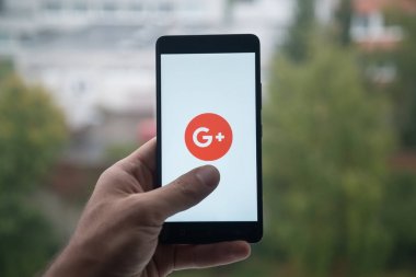 Smartphone ile Google plus parmak ile logo üstünde belgili tanımlık perde tutan adam.