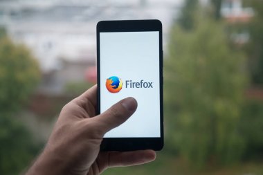 Üstünde belgili tanımlık perde smartphone ile Mozilla firefox logosu ile parmak tutan adam.