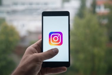Üstünde belgili tanımlık perde smartphone parmaklı Instagram logolu tutan adam.