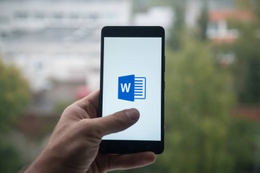 Üstünde belgili tanımlık perde smartphone parmak ile Microsoft Office word logolu tutan adam.