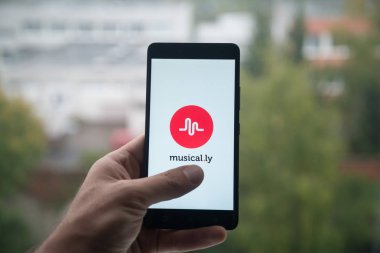 Üstünde belgili tanımlık perde smartphone ile parmak Musical.ly logolu tutan adam.