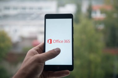 Üstünde belgili tanımlık perde smartphone parmak ile Microsoft Office 365 logolu tutan adam.
