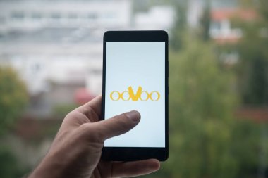 Üstünde belgili tanımlık perde smartphone parmak ile Oovoo logolu tutan adam.