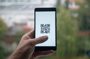 Üstünde belgili tanımlık perde smartphone ile Qr kod parmaklı tutan adam.