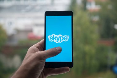 Smartphone ile parmak ile Skype logo üstünde belgili tanımlık perde tutan adam.