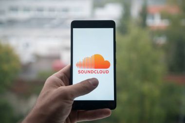 Üstünde belgili tanımlık perde smartphone parmaklı Soundcloud logolu tutan adam.