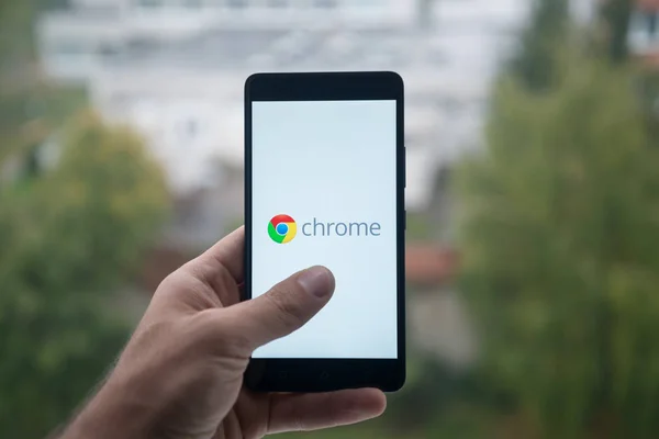 Homme tenant smartphone avec logo Google Chrome avec le doigt sur l'écran . — Photo