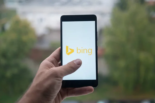 Hombre sosteniendo el teléfono inteligente con el logotipo de Bing con el dedo en la pantalla . —  Fotos de Stock