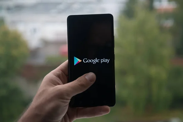 Чоловік тримає смартфон з Google play store логотип з пальця на екран. — стокове фото