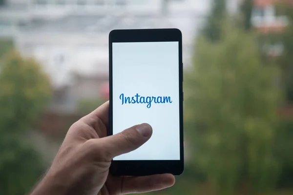 Üstünde belgili tanımlık perde smartphone parmaklı Instagram logolu tutan adam. — Stok fotoğraf