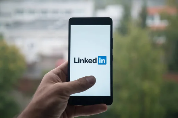 Man holding smartphone with Linkedin logo with the finger on the screen. — Stock Photo, Image