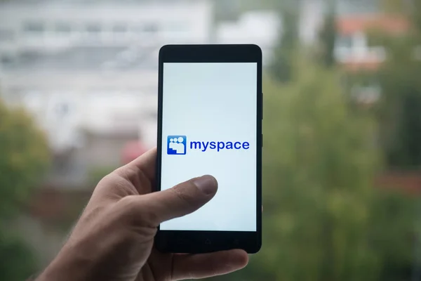 Man met smartphone met Myspace logo met de vinger op het scherm. — Stockfoto