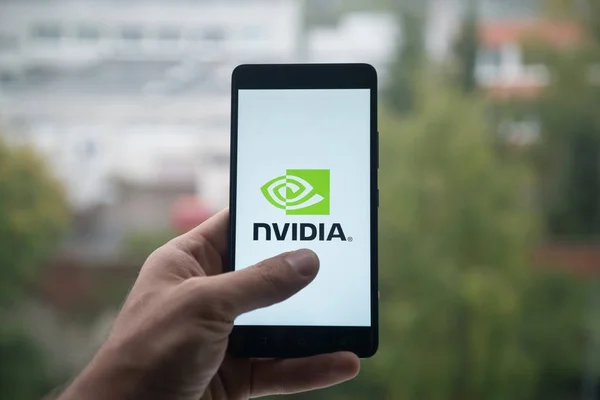 男子手持智能手机与 Nvidia 的标志，用手指在屏幕上. — 图库照片