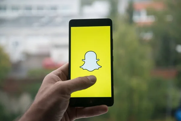 Üstünde belgili tanımlık perde smartphone ile parmak Snapchat logolu tutan adam.